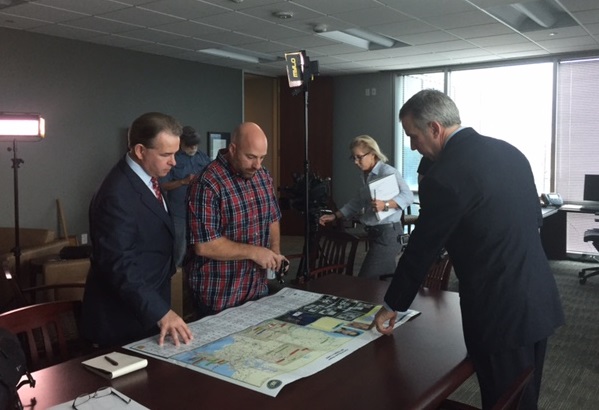 An image of Special Agent in Charge of the Houston Field Division Fred Milanowski talking to news crew as Nicole Strong works in the background