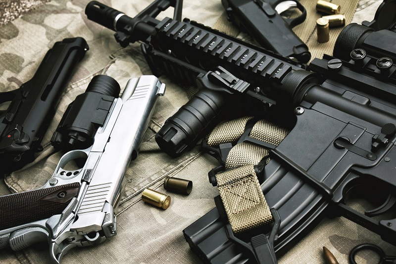 Several firearms laid on top of a camouflage cover 