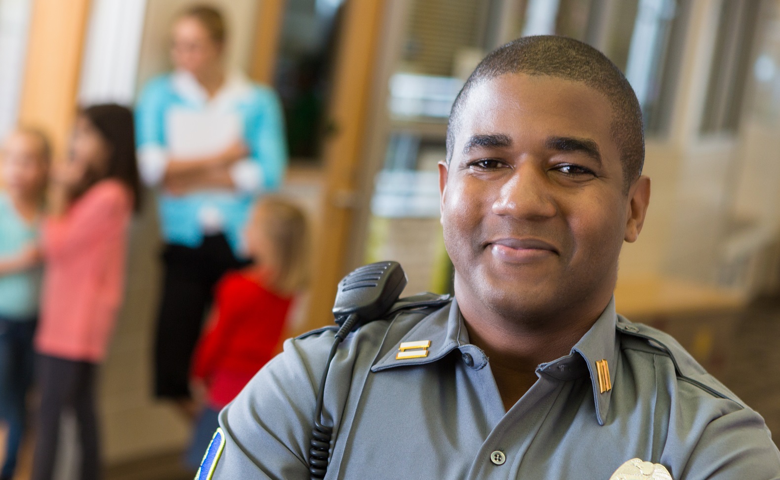 school guard in hallway as students stand by a classroom