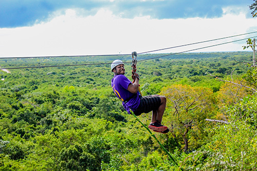 Brandon zip lines above the tree tops.