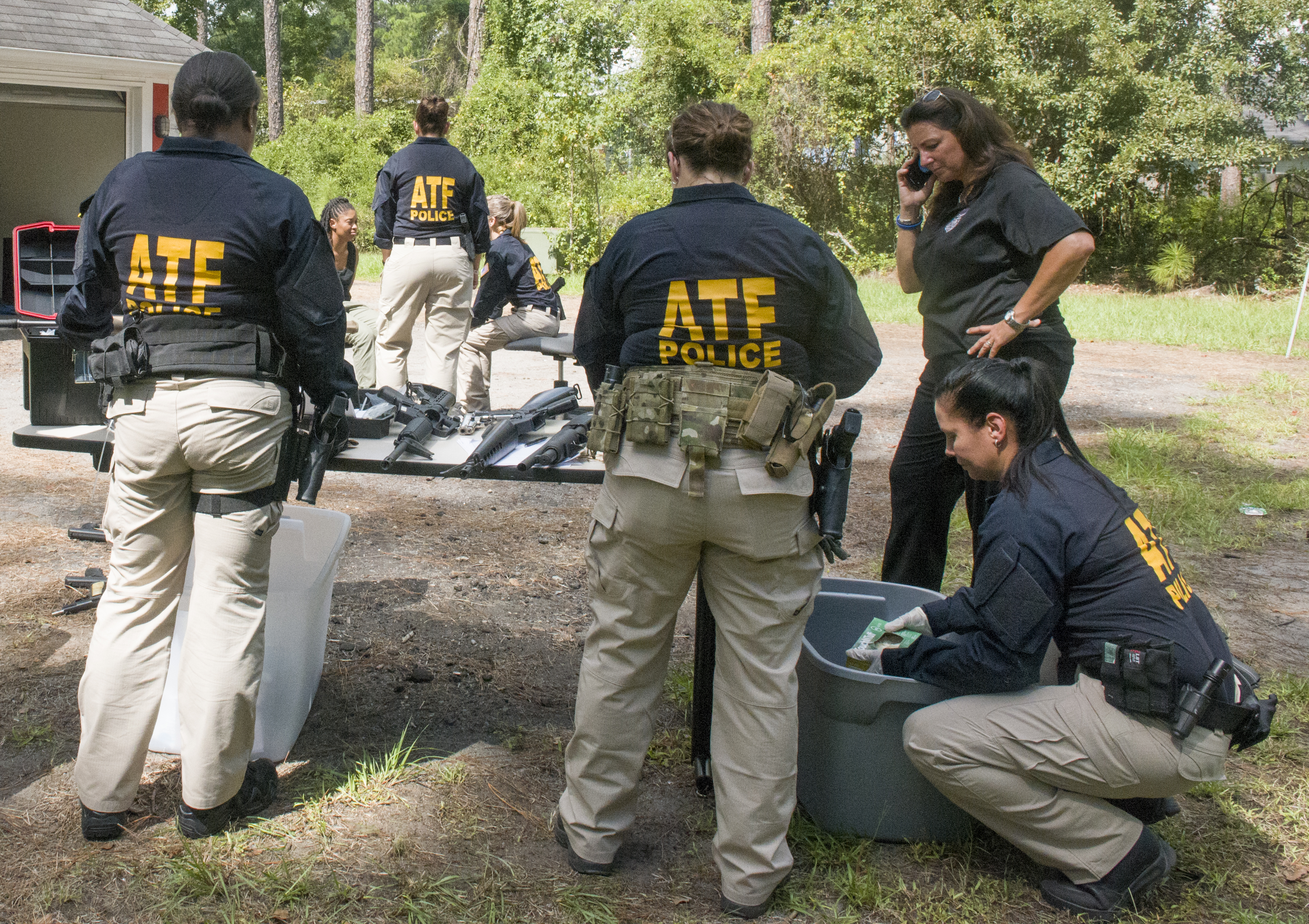 Industry Operations Investigators review evidence found at a straw gun house 