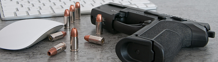 Gun and bullets on a desk next to a computer Gun and bullets on a desk next to a computer