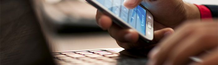 Image of a person using a laptop and a smartphone