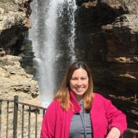 Misty stands in front of a waterfall