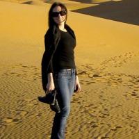 Cara stands in front of sand dunes.